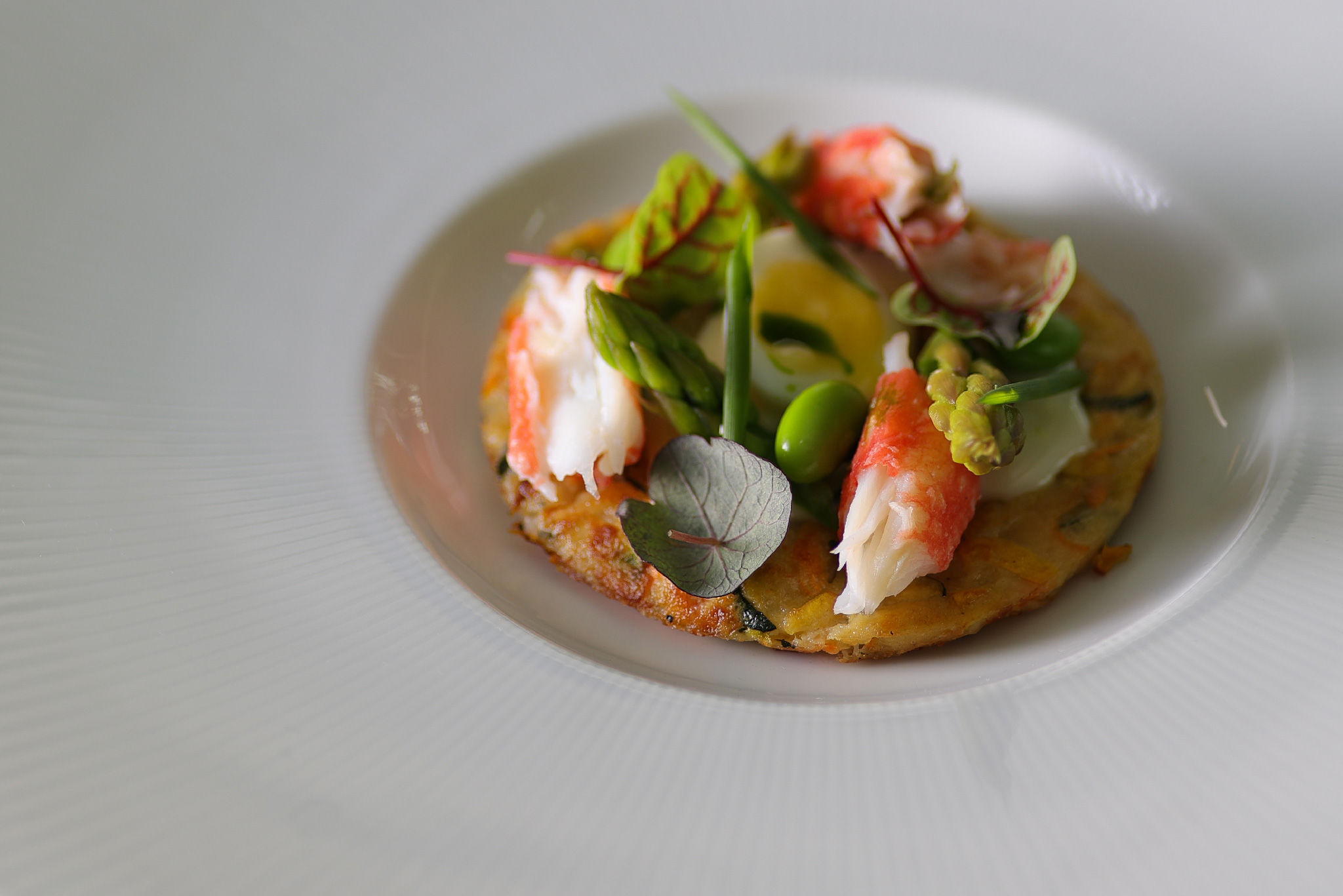 Rösti with Stracciatella cheese, Kamchatka crab, quail egg, and green vegetables